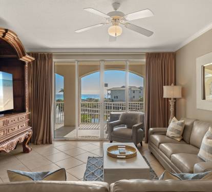 Unwind in the elegant living space with leather seating, entertainment center, and stunning balcony views of the coastline beyond.