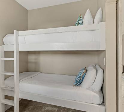 Cozy bunk beds with crisp white linens and cheerful blue accents create the perfect space for your family's comfort.