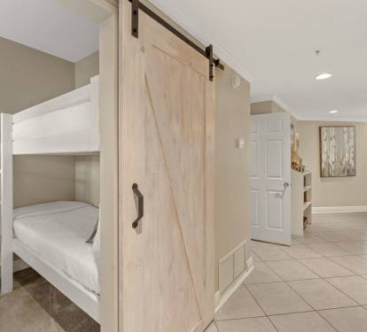 Kids will love this clever bunk bed setup with a rustic barn door for privacy and cozy carpeted floors.