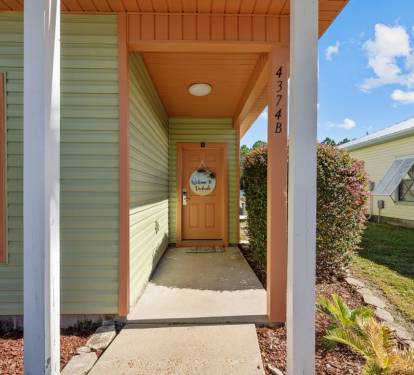 A bright welcome awaits at this cheerful cottage entrance with its mint green siding and warm orange accents under sunny Florida skies.