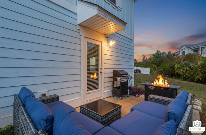 Private outdoor patio with comfortable lounge seating, fire pit table, and BBQ grill perfect for relaxing evenings, grilling meals, and enjoying quality time outdoors in a cozy setting.