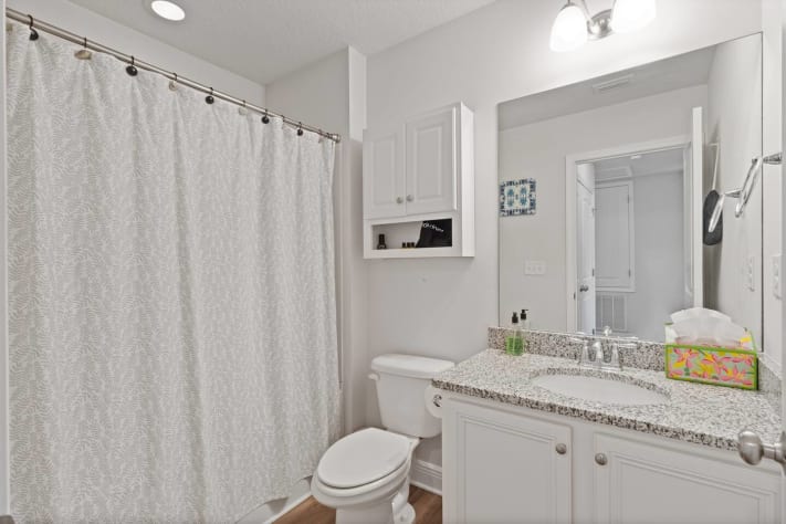 Bright and spotless bathroom vanity with granite countertop, large mirror, and extra storage. Thoughtfully stocked with essentials and fresh towels for a comfortable, convenient stay.