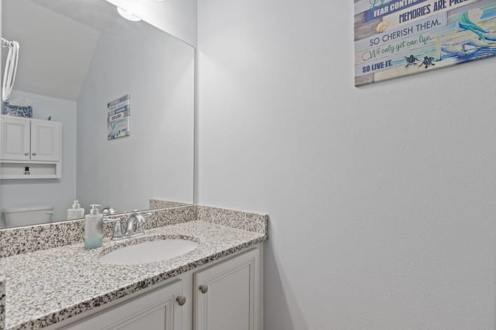 Bright and spotless bathroom vanity with granite countertop, large mirror, and extra storage. Thoughtfully stocked with essentials and fresh towels for a comfortable, convenient stay.