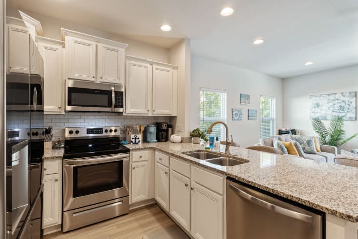 Modern, fully equipped kitchen with stainless steel appliances, granite countertops, and ample cabinet space. Bright and open layout with bar seating perfect for cooking, entertaining, or enjoying meals together during your stay.
