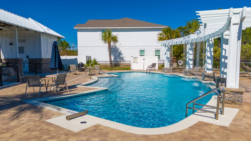 Resort-style community pool with plenty of lounge chairs and shaded seating. 