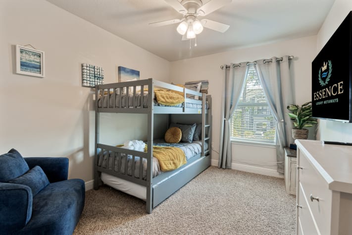Spacious bunk room perfect for families and kids, featuring cozy beds, soft linens, and a wall-mounted TV. Bright natural light, comfortable seating, and playful d&eacute;cor create a fun and relaxing space for everyone.