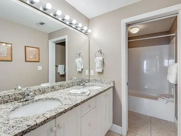 Wellâ€‘stocked master bathroom with dual sinks&mdash;bright, modern, and beachâ€‘inspired