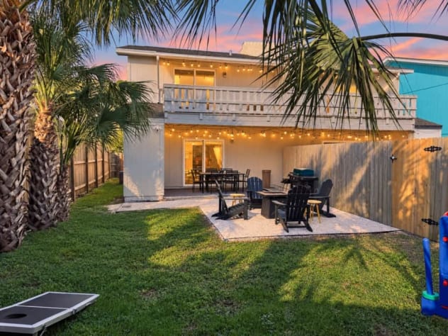 Enjoy Unit A's covered patio for outdoor meals, then gather around the fire pit or play backyard games beneath the palms. Upstairs, the king suite opens onto its own covered balcony. A garden gate connects this yard with Unit B's outdoor space