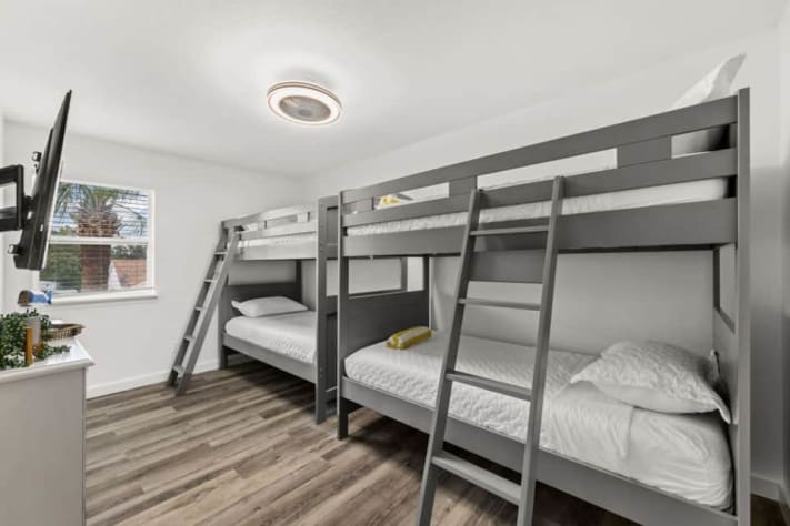 Unit B's upstairs bunk room has two twin-over-twin bunk beds, giving four guests their own sleeping space. A smart TV and storage add everyday convenience. The room shares the full hallway bathroom, with a bathtub and shower, with the queen bedroom