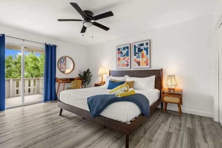 Unit A's king suite sleeps two and includes a smart TV, dedicated desk, closet storage, and a private covered balcony with cushioned seating. The ensuite has a walk-in shower and a toilet with a bidet. Bed linens and towels are provided