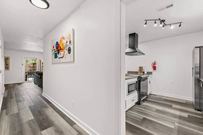 Welcome to Unit A, the right-hand home when facing the duplex. The downstairs layout connects the kitchen, dining area, and smart-TV lounge, with a half bathroom and laundry nearby. Three bedrooms and two full bathrooms are located upstairs