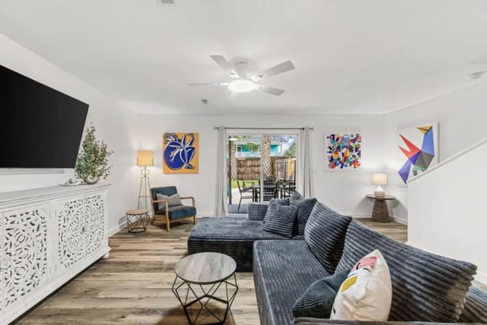 Unwind on Unit B's oversized sectional with a large smart TV and high-speed Wi-Fi. Colorful abstract art and midcentury-inspired furniture brighten the lounge, while sliding doors connect movie nights indoors with patio dining and backyard games