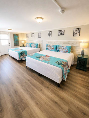 A Double King Suite features a private exterior entry door and two king-size beds.  Two dressers and a smart TV