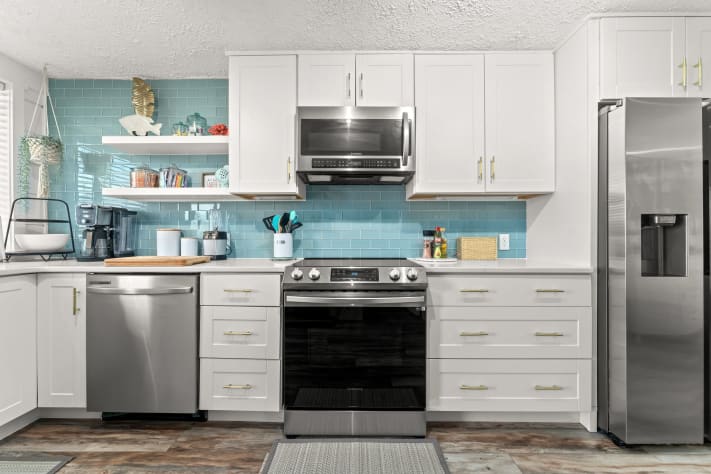 New stainless steel appliances and glass backsplash.