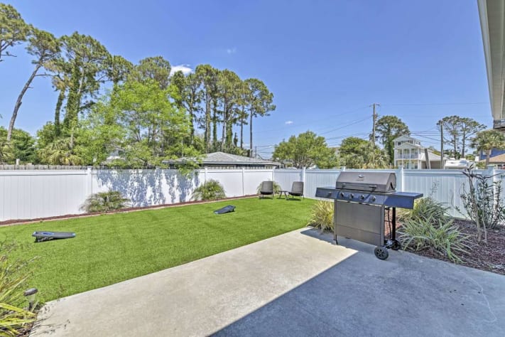 The secluded backyard includes lawn games, furniture, and a grill