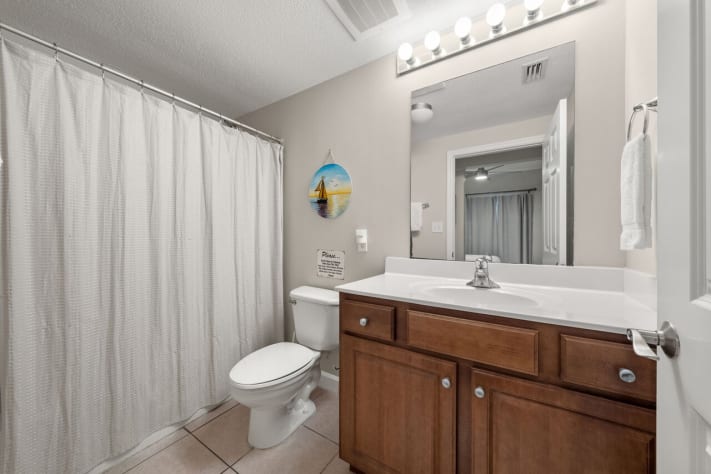 Clean coastal bathroom with tub shower, vanity lighting, and ample counter space