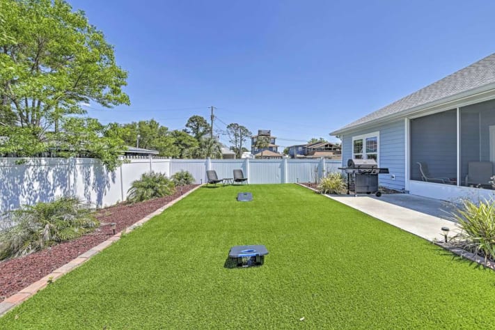 The secluded backyard includes lawn games, furniture, and a grill
