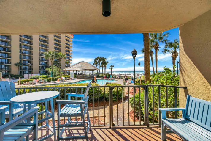 Balcony with high top table, three chairs, bench and small table.