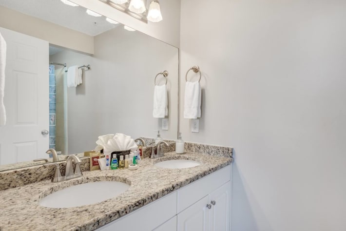 Primary bathroom has granite countertops, dual vanities, and shower/tub combo