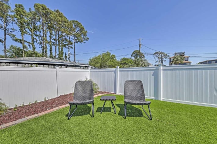 The secluded backyard includes lawn games, furniture, and a grill