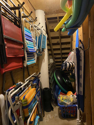 Toy closet loaded with beach chairs, umbrellas, pool toys, beach toys, baby pool