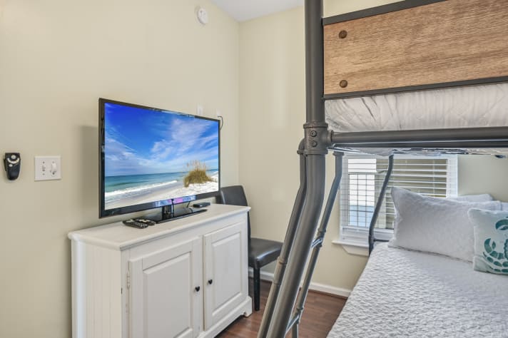 Secondary bedroom features a QUEEN over twin, TV, closet, and attached bathroom with shower/tub combo