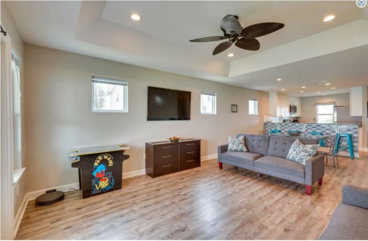 The great room features 2 arcade machines, 2 futons, and a smart TV