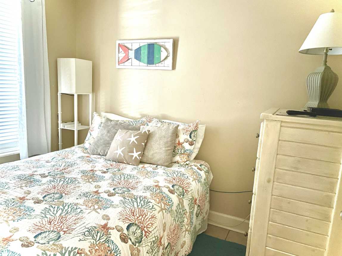 Queen bedroom with tall dresser and 32 inch TV