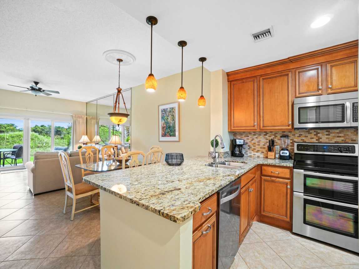 Very well lit kitchen with pendant lights and ceiling lights with a small chandelier over the dining table.