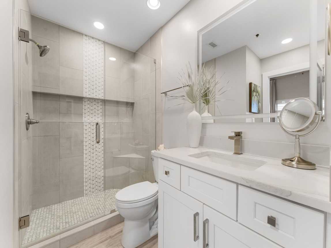 Bath is a single vanity with mirror and cabinet storage.  Oversized tiled shower with shower seat and ledge for all your bath amenities.