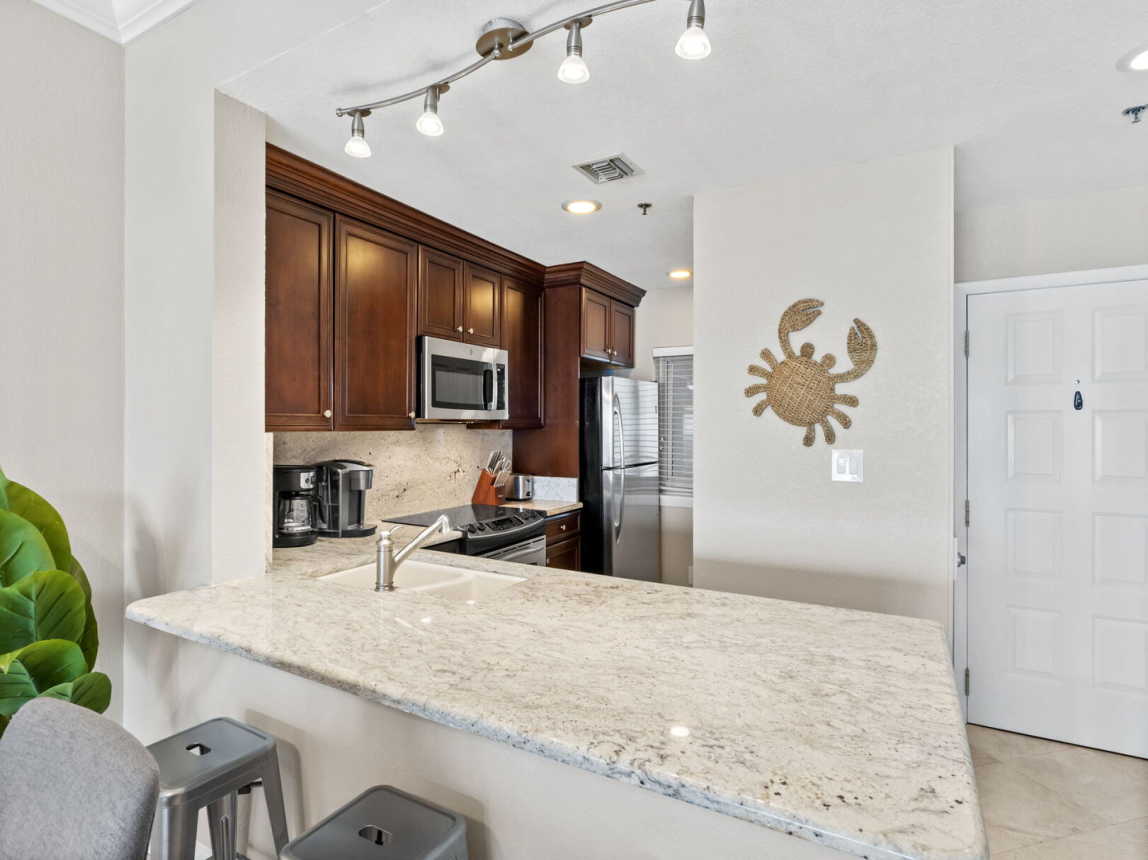 View into the fully stocked kitchen with all stainless steele appliances, cookware, drinkware, dinner ware, coffee pot, toaster. Full size refrigerator.