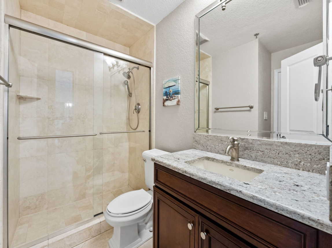 Guest bath offers oversized step-in shower, single vanity, mirror and toilet .