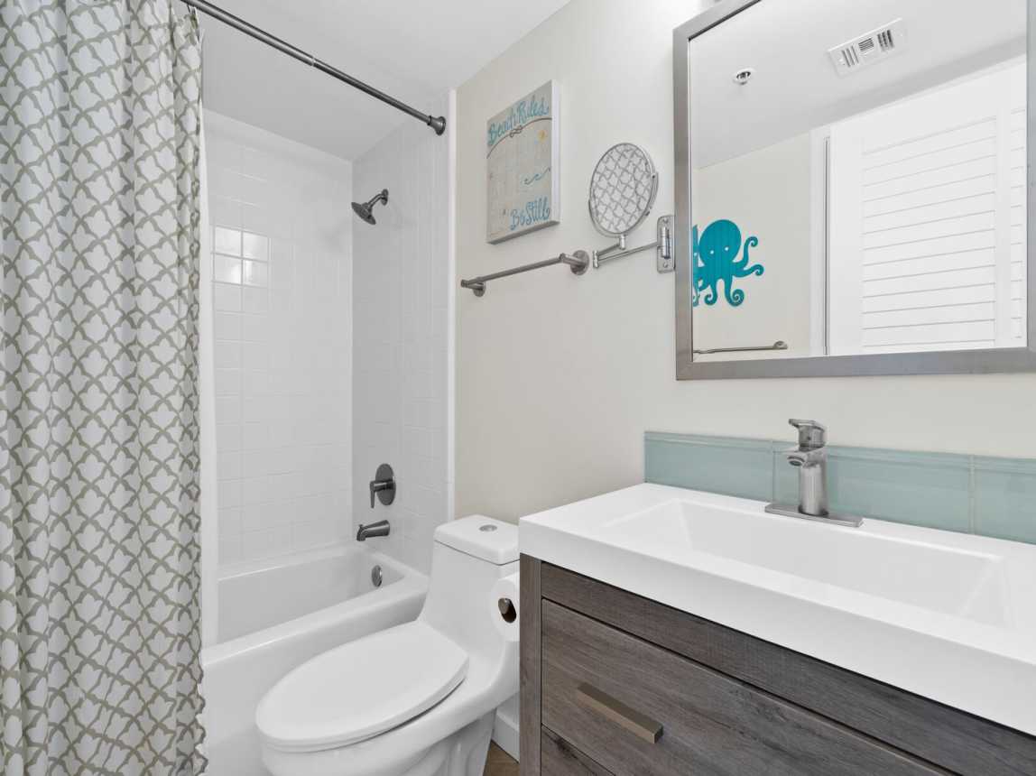 The guest bath is a shared bath for the two guest bedrooms. Offering a large vanity, wall mirror, bath/tub combo.