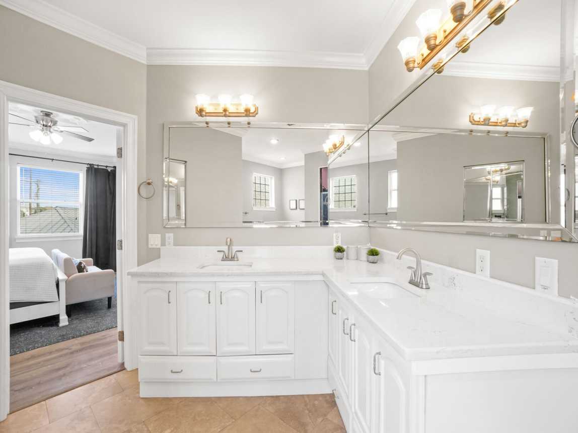 Enjoy this oversize ensuite bathroom with double vanities, wall mirrors, plenty of lighting and sotrage.