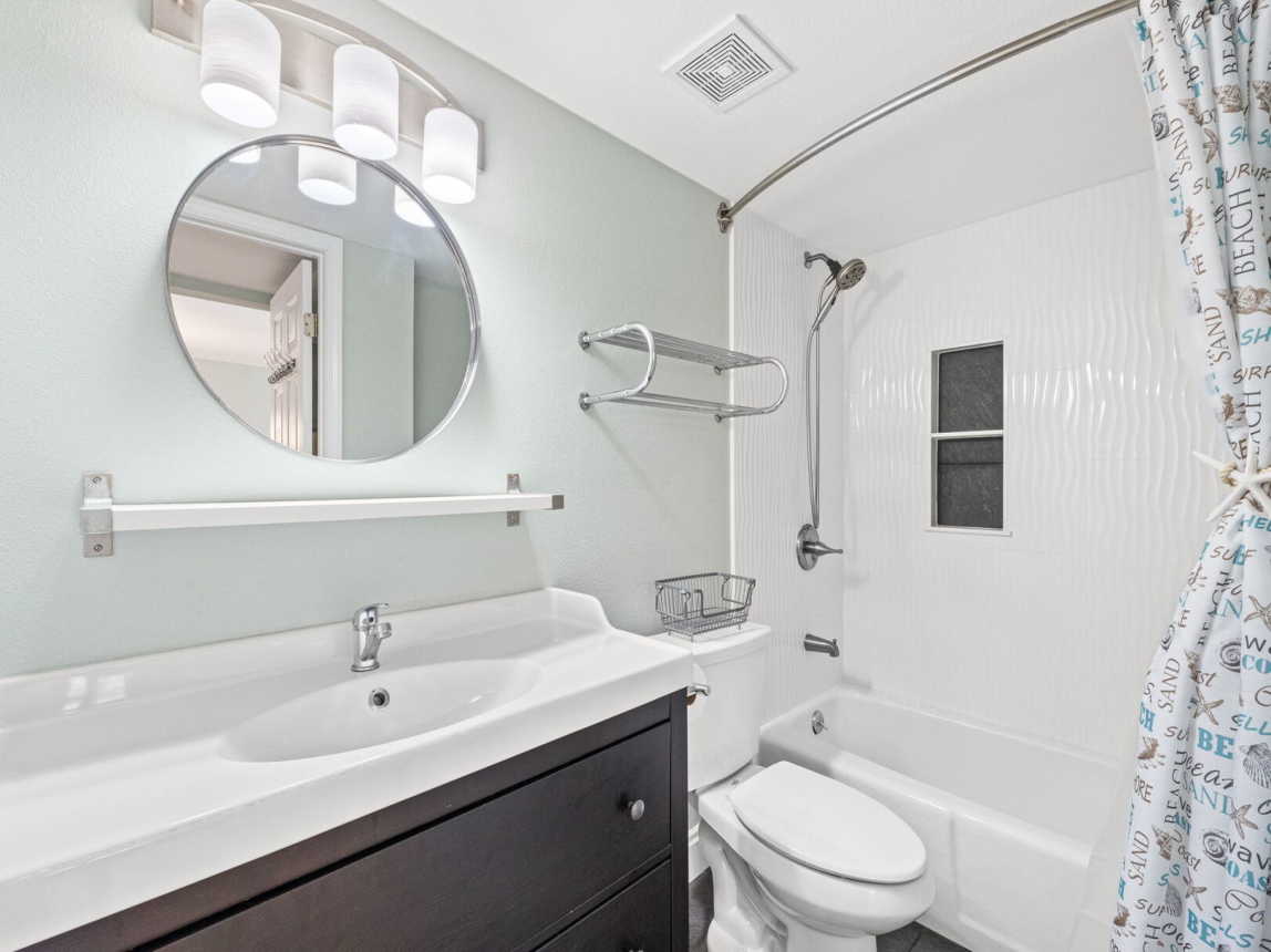 Remodeled guest batch with tub/shower combo, large vanity and mirror, with handheld shower spray.