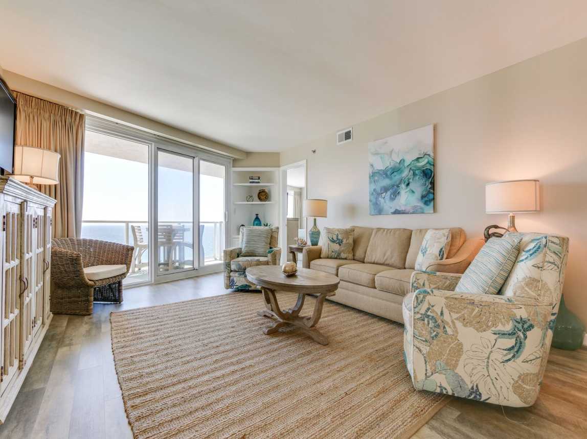 Living Room area includes a sleeper sofa, sitting chairs, and a large flat screen TV with cable. Door access to private balcony.