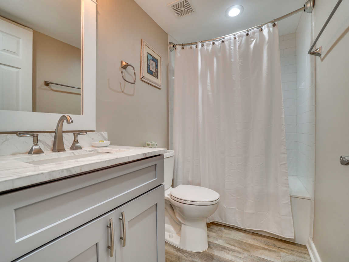 Guest bathroom has a single vanity and shower/tub combo.