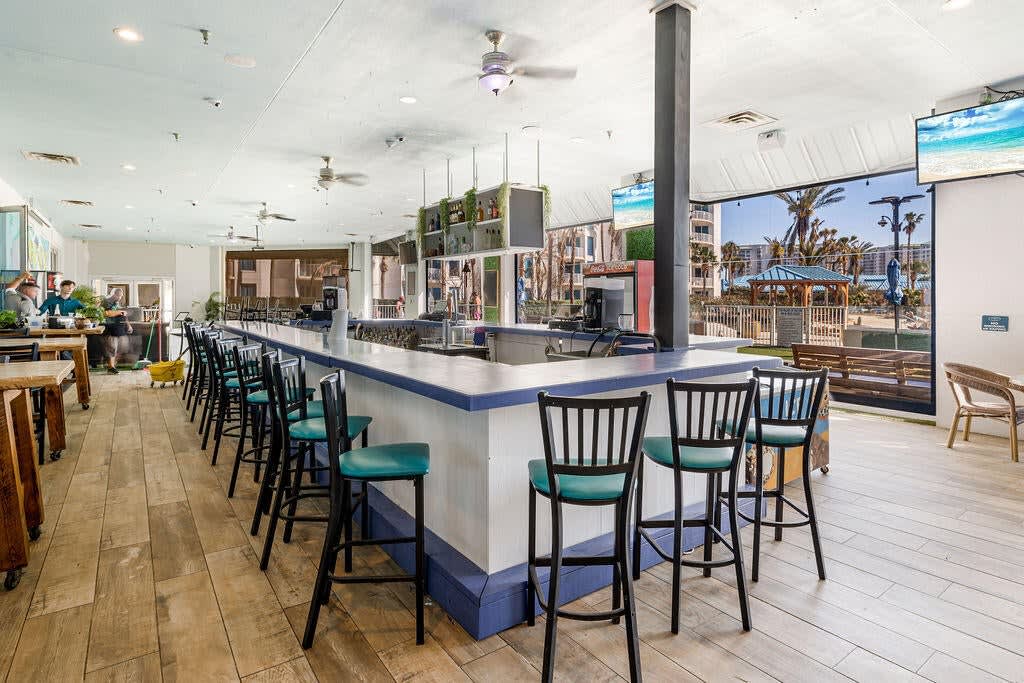 Poolside food & drink area w/ shaded seating and a casual resort feel.