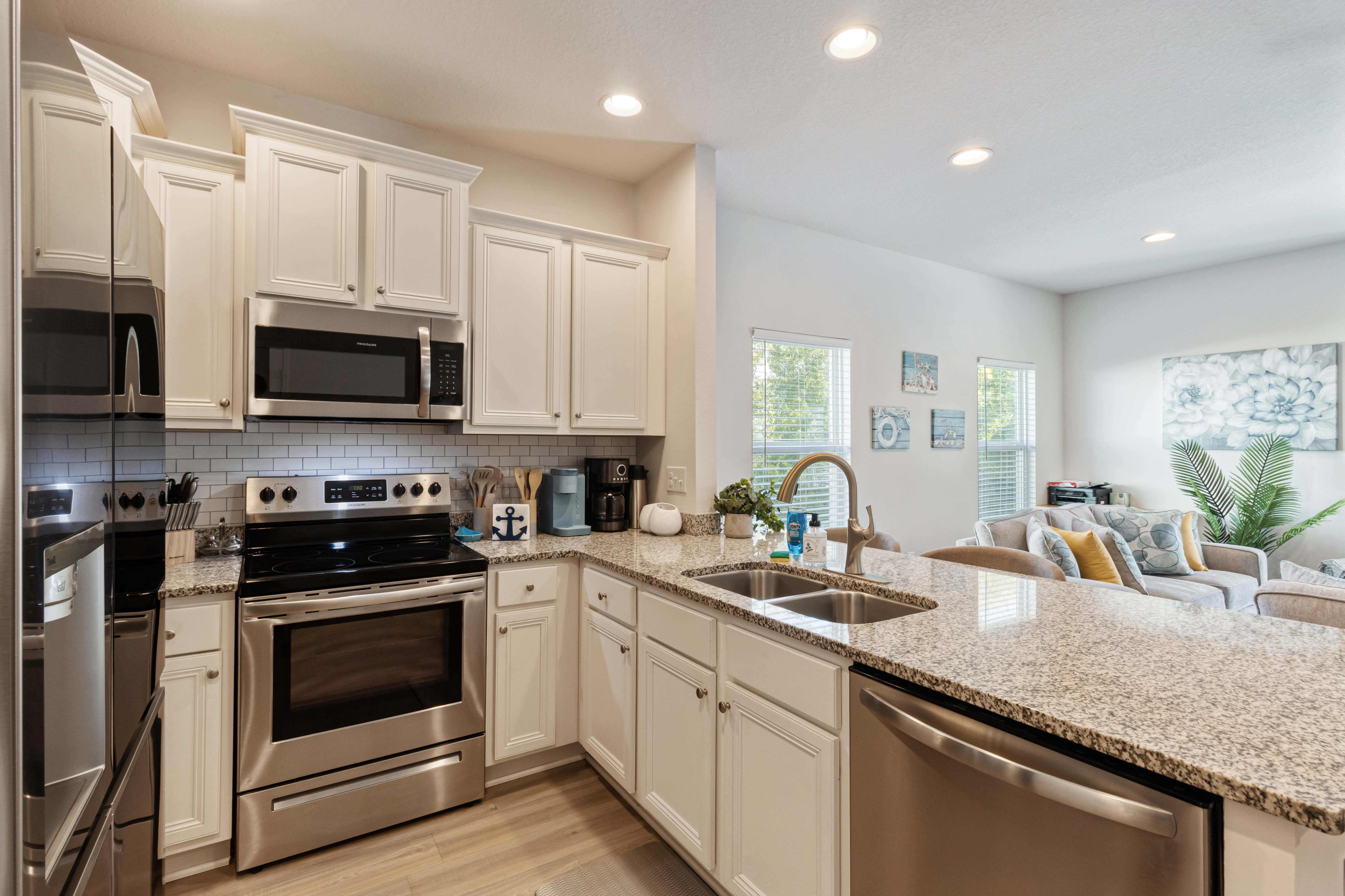 Modern, fully equipped kitchen with stainless steel appliances, granite countertops, and ample cabinet space. Bright and open layout with bar seating perfect for cooking, entertaining, or enjoying meals together during your stay.