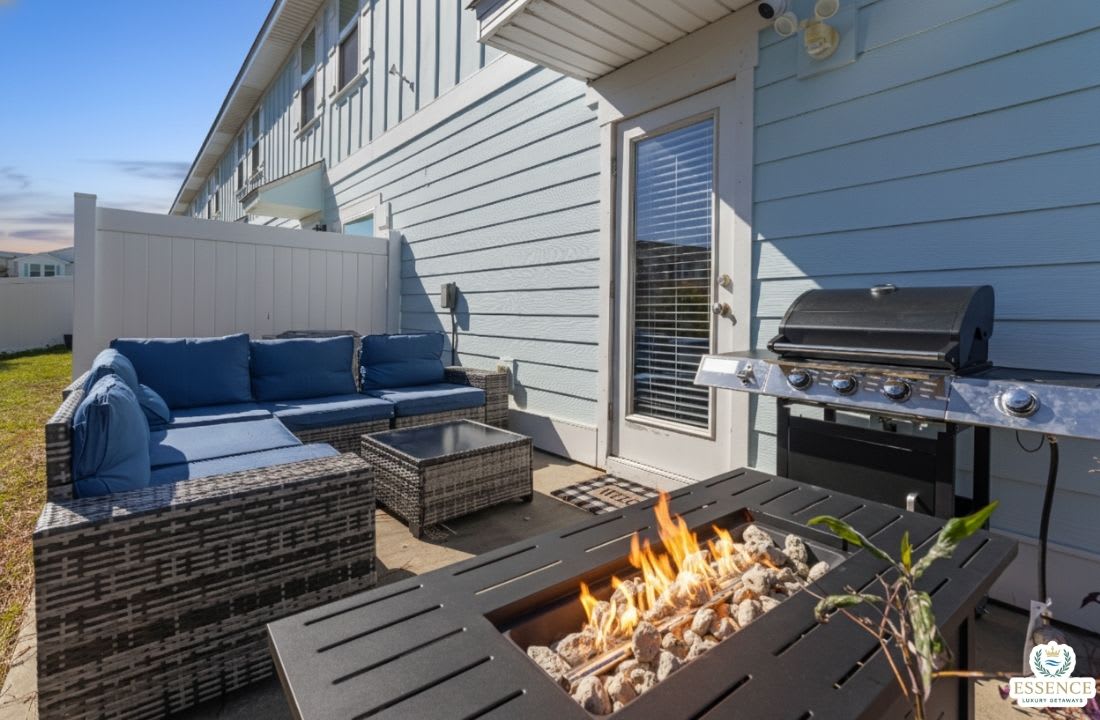 Private outdoor patio with comfortable lounge seating, fire pit table, and BBQ grill perfect for relaxing evenings, grilling meals, and enjoying quality time outdoors in a cozy setting.