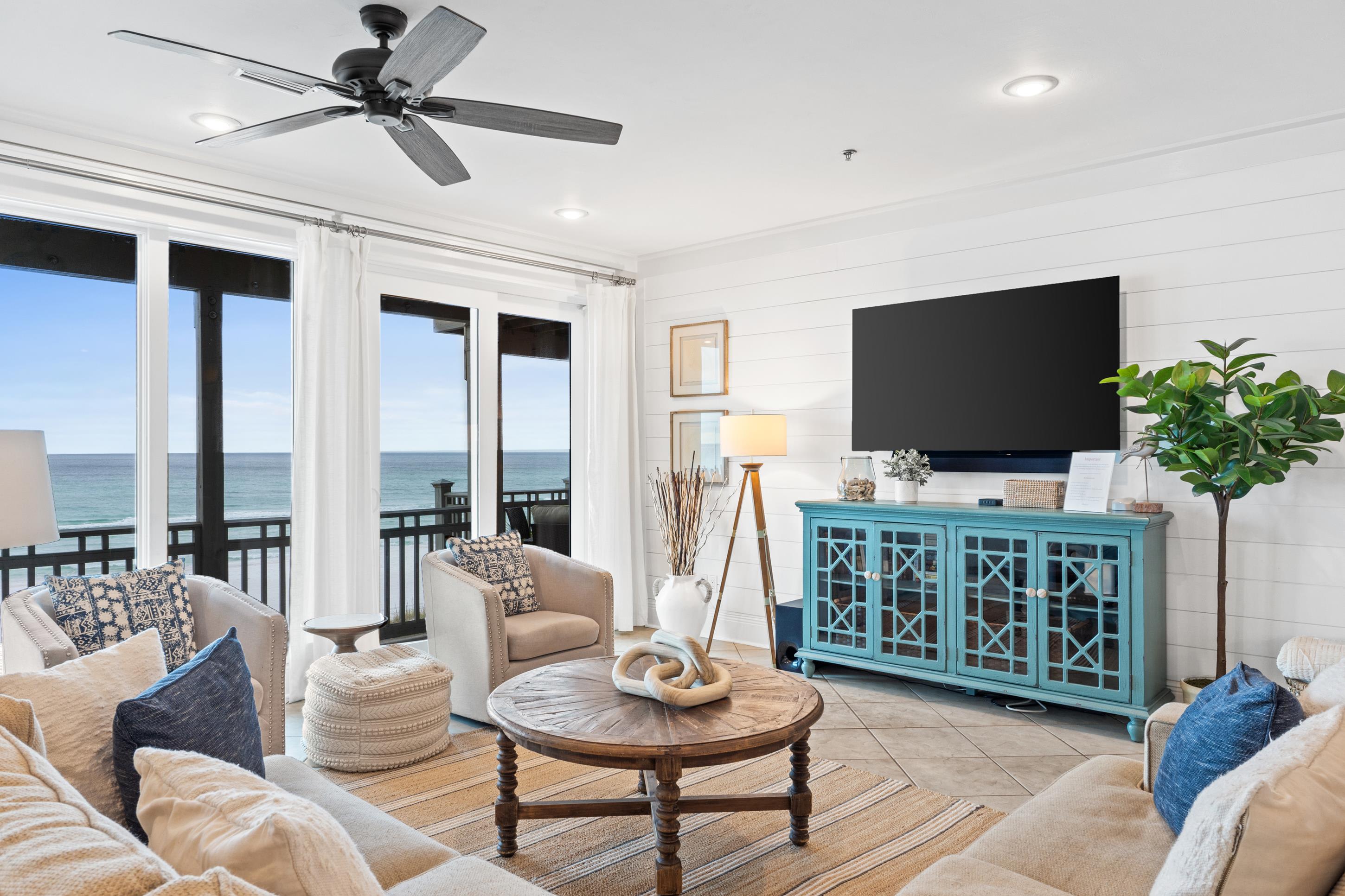 Stylish Gulf-view living room with modern coastal d&eacute;cor and large TV&mdash;perfect for relaxing after a day at the beach while still enjoying the breathtaking views right outside your window.