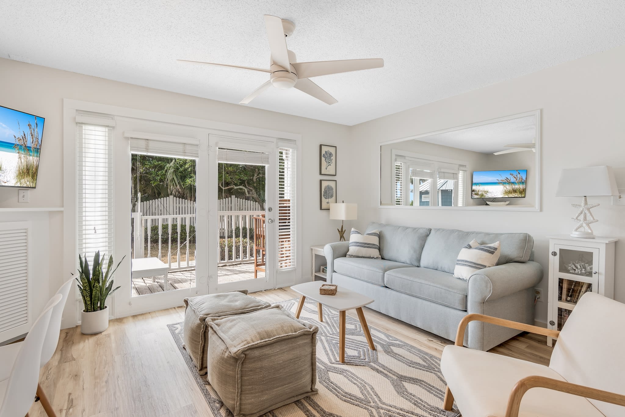 Bright and airy living room with a comfy sleeper sofa, cozy seating for all, and a ceiling fan. 