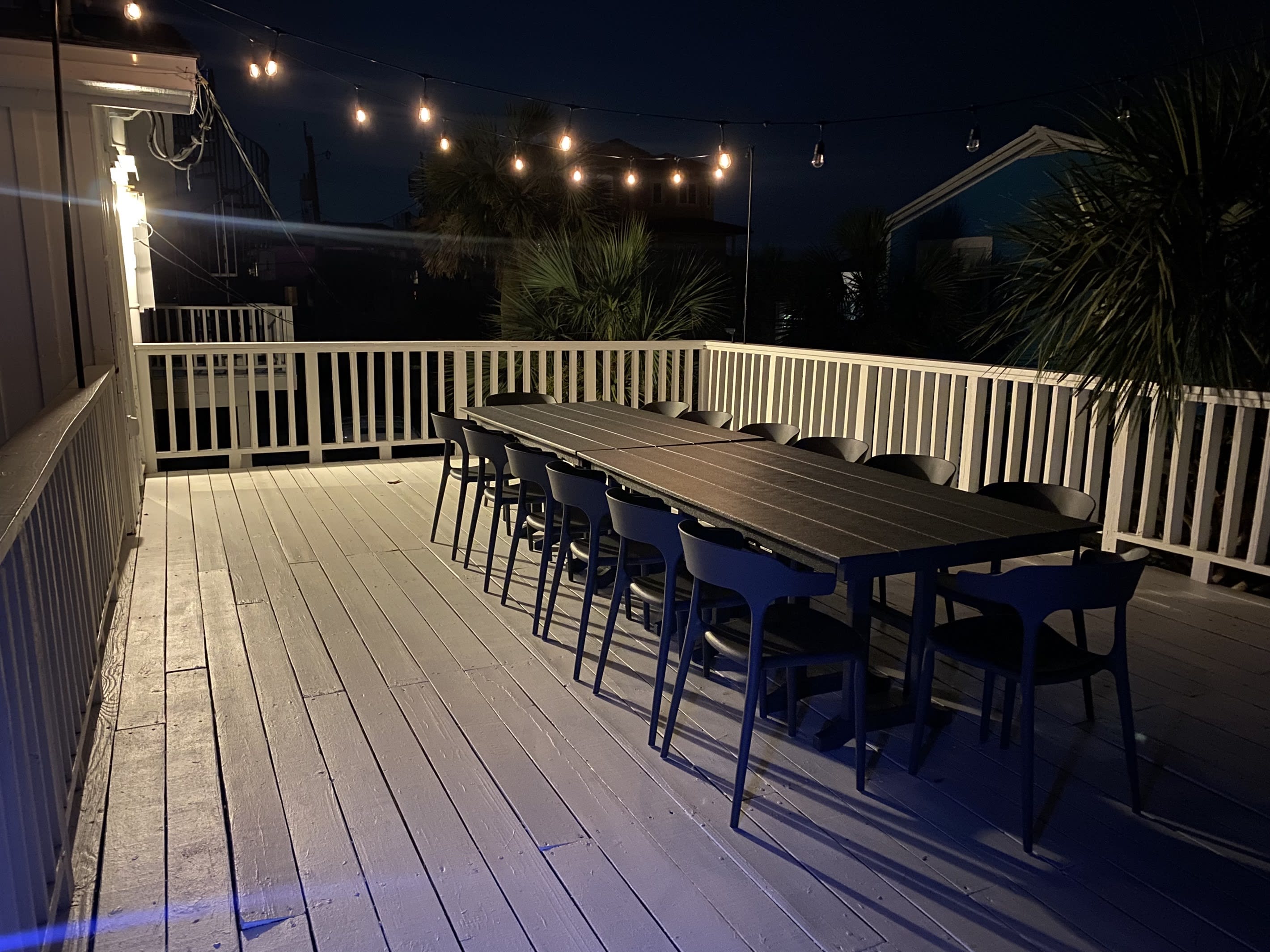 A spacious outdoor dining table awaits on the deck, offering seating for up to 14 guests. Adorned with charming string lights, it's the perfect spot for al fresco dining under the stars. Just steps away from the kitchen, convenience meets ambiance.