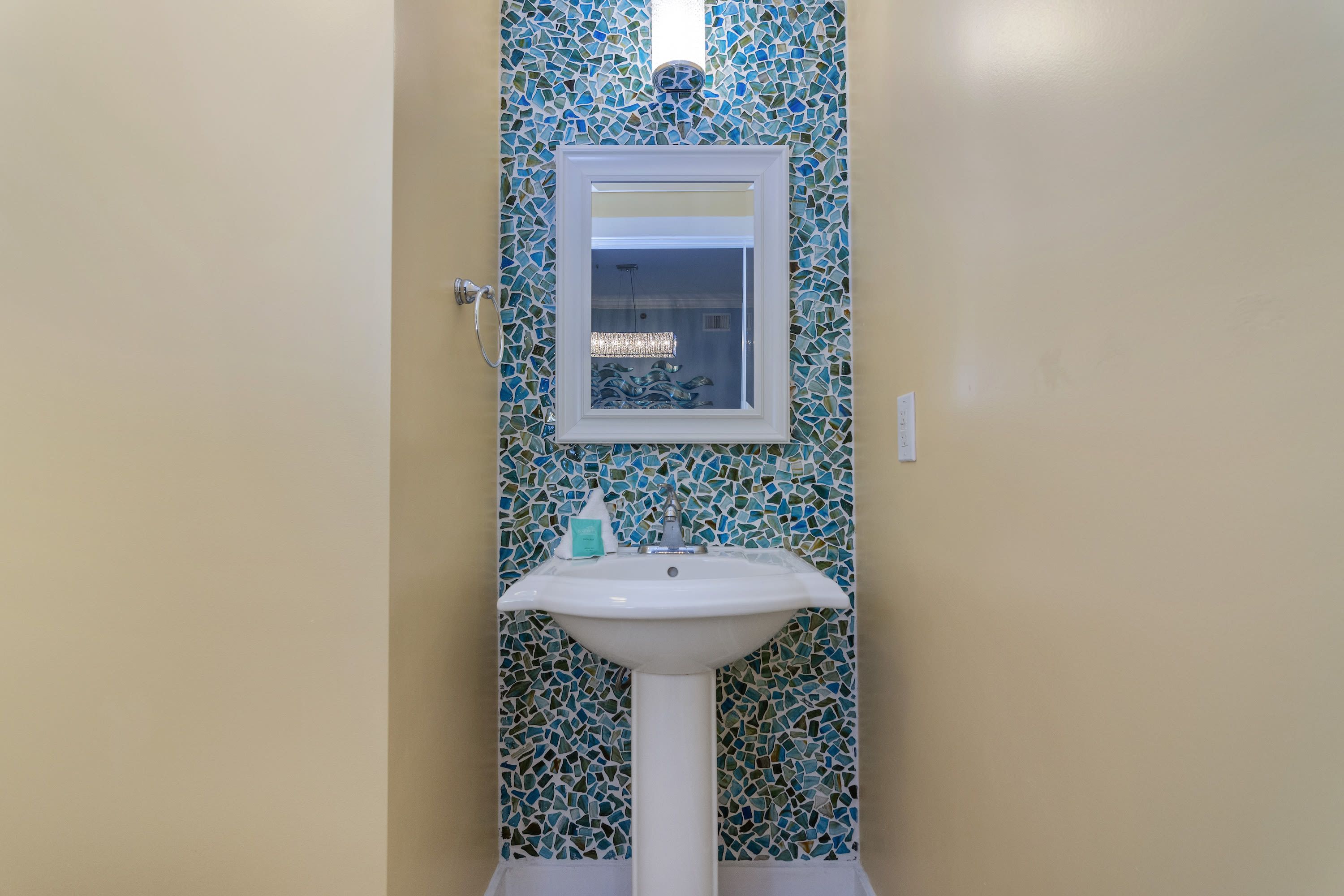 Even the guest half bathroom has an ocean vibe with the glass pebble wall