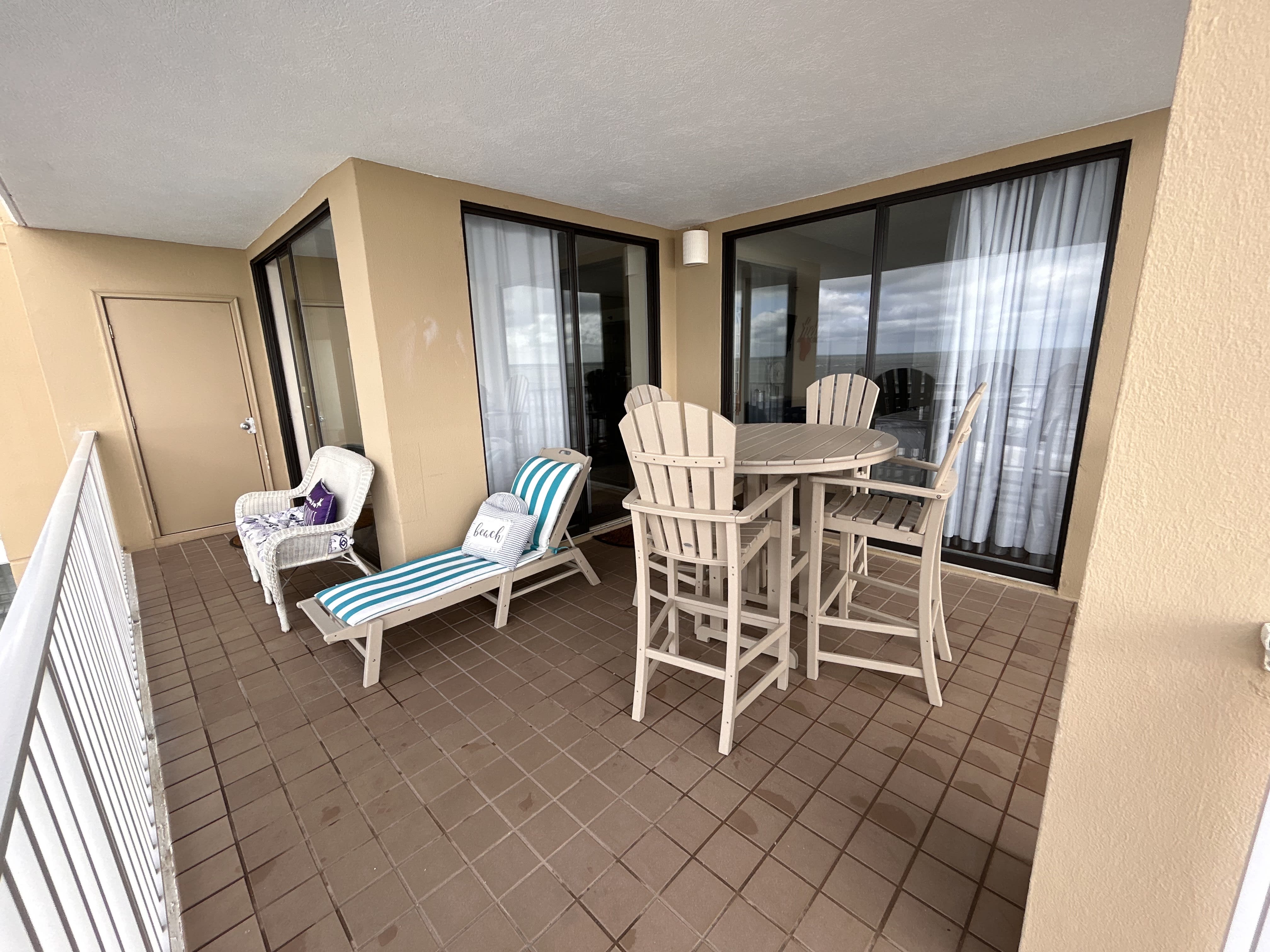 Beach view balcony seating with table and chairs, lounge chair and wicker sofa