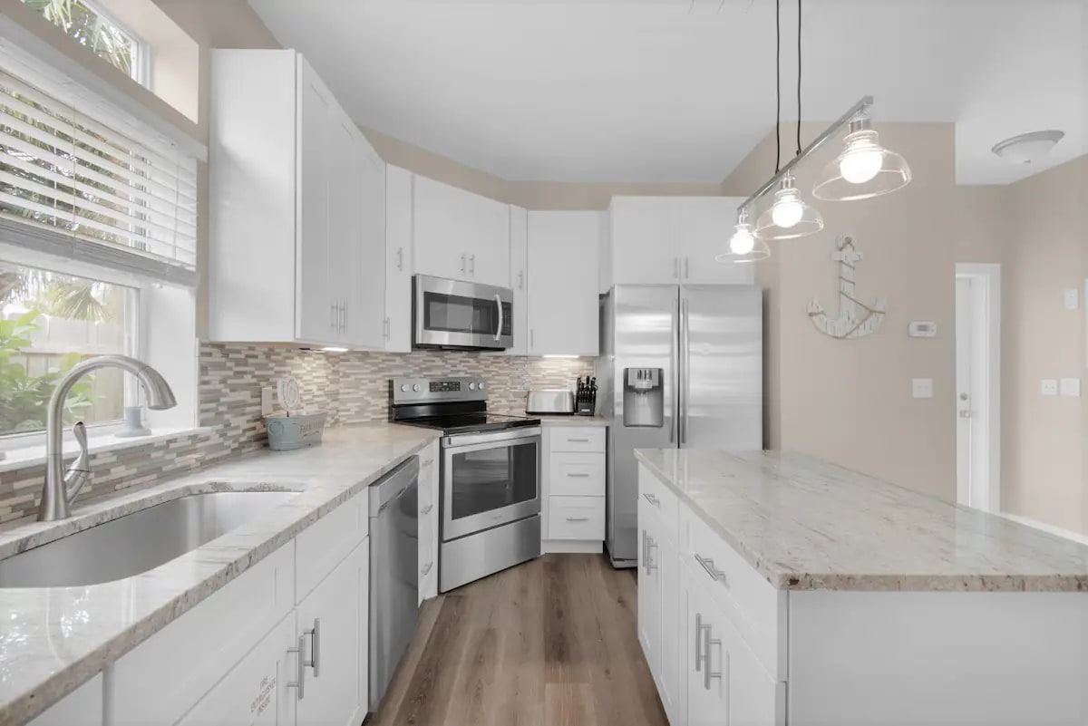 Sunkissed-15 kitchen features granite counters, stainless appliances and farm sink.