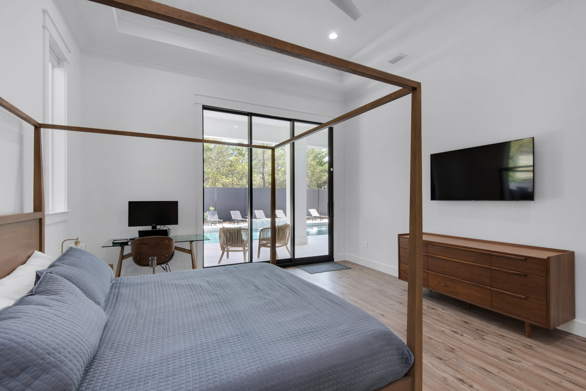 King Master bedroom with desk, and glass doors that lead you to the pool area.