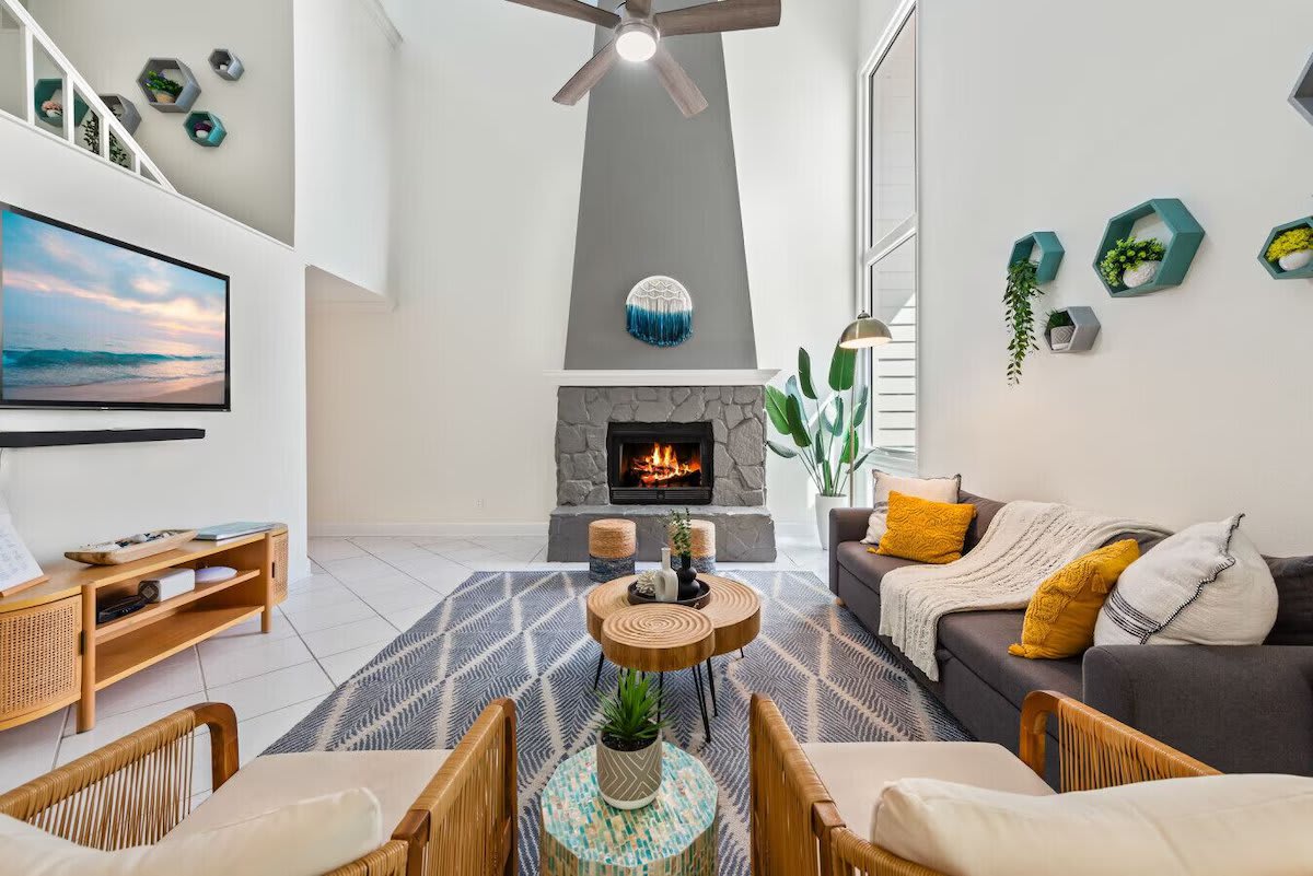 Cozy up at Seabreeze Villa ðŸ”¥ This inviting living room features a warm fireplace and coastal-inspired decor&mdash;perfect for relaxing after a day at the beach. Your seaside escape is just a booking away! ðŸŒ´âœ¨