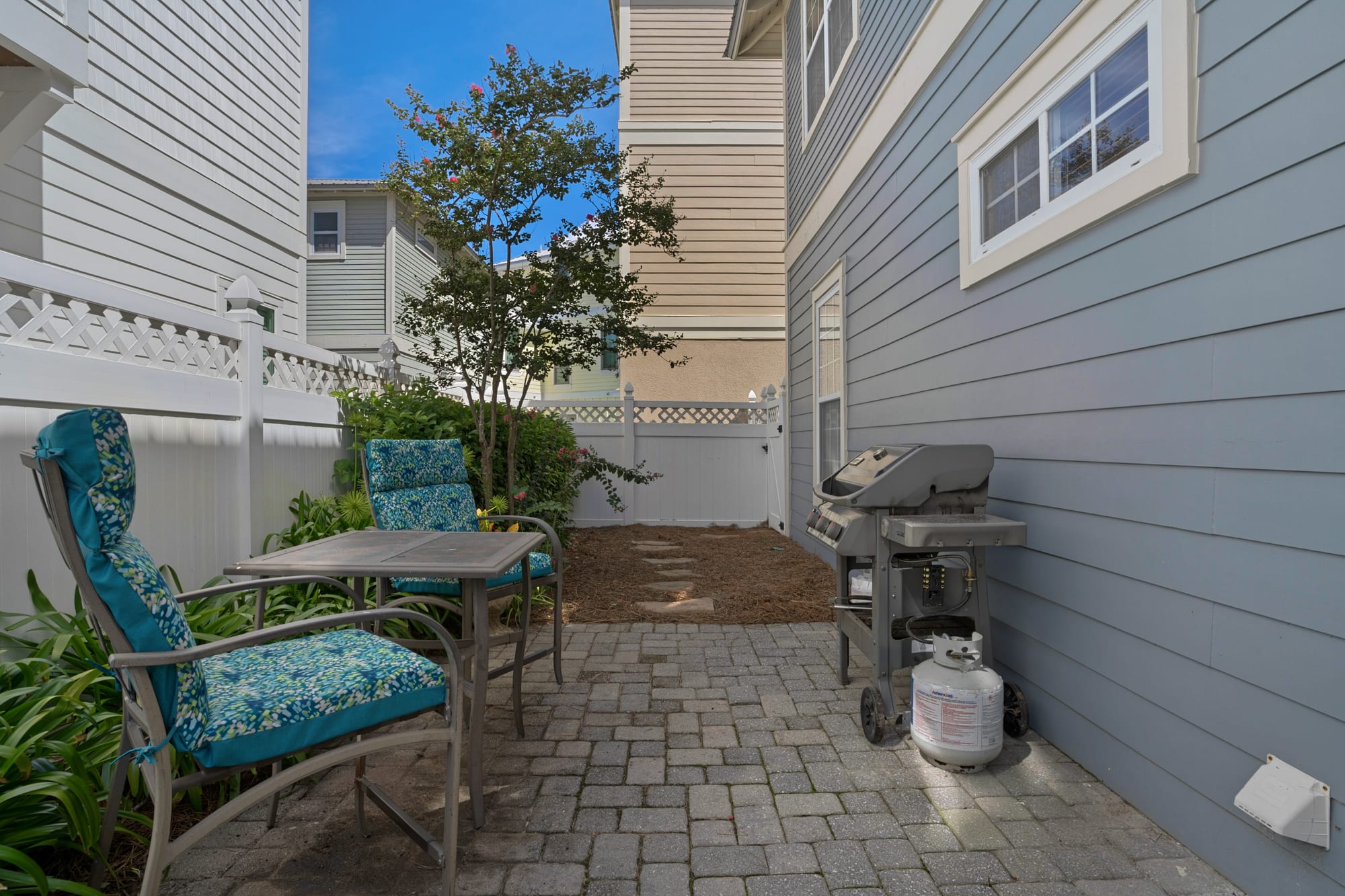 Private backyard and patio area with seating and gas grill.