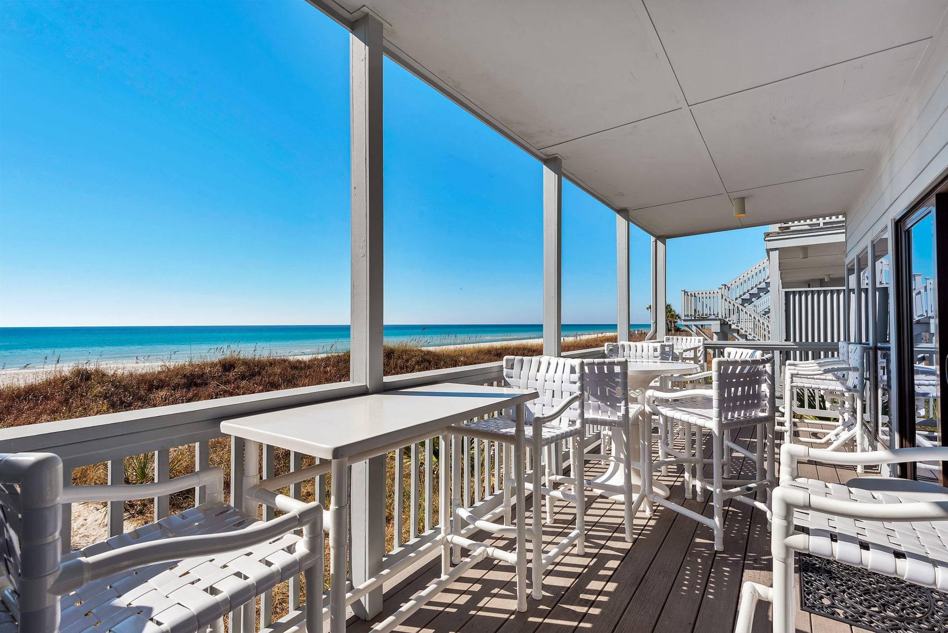 Deck that is Adjacent with the Beach and Ocean and has Seating for 10 Guests and Tables